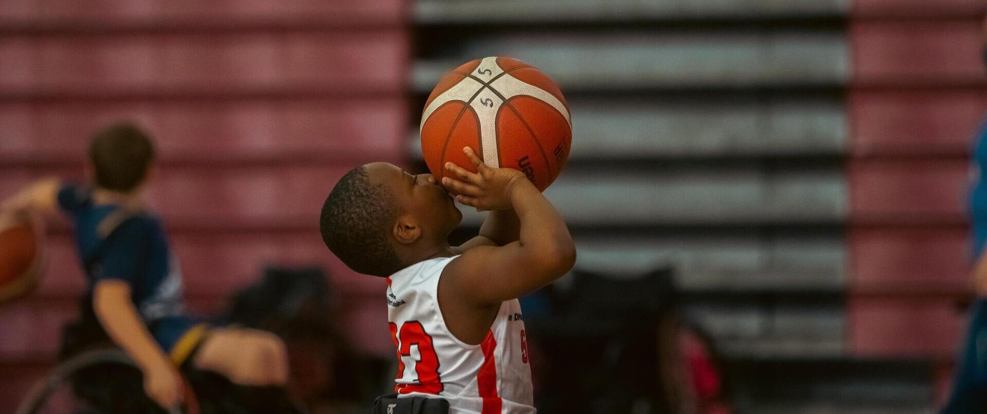 Photo représentant un enfant en fauteuil faisant du basket